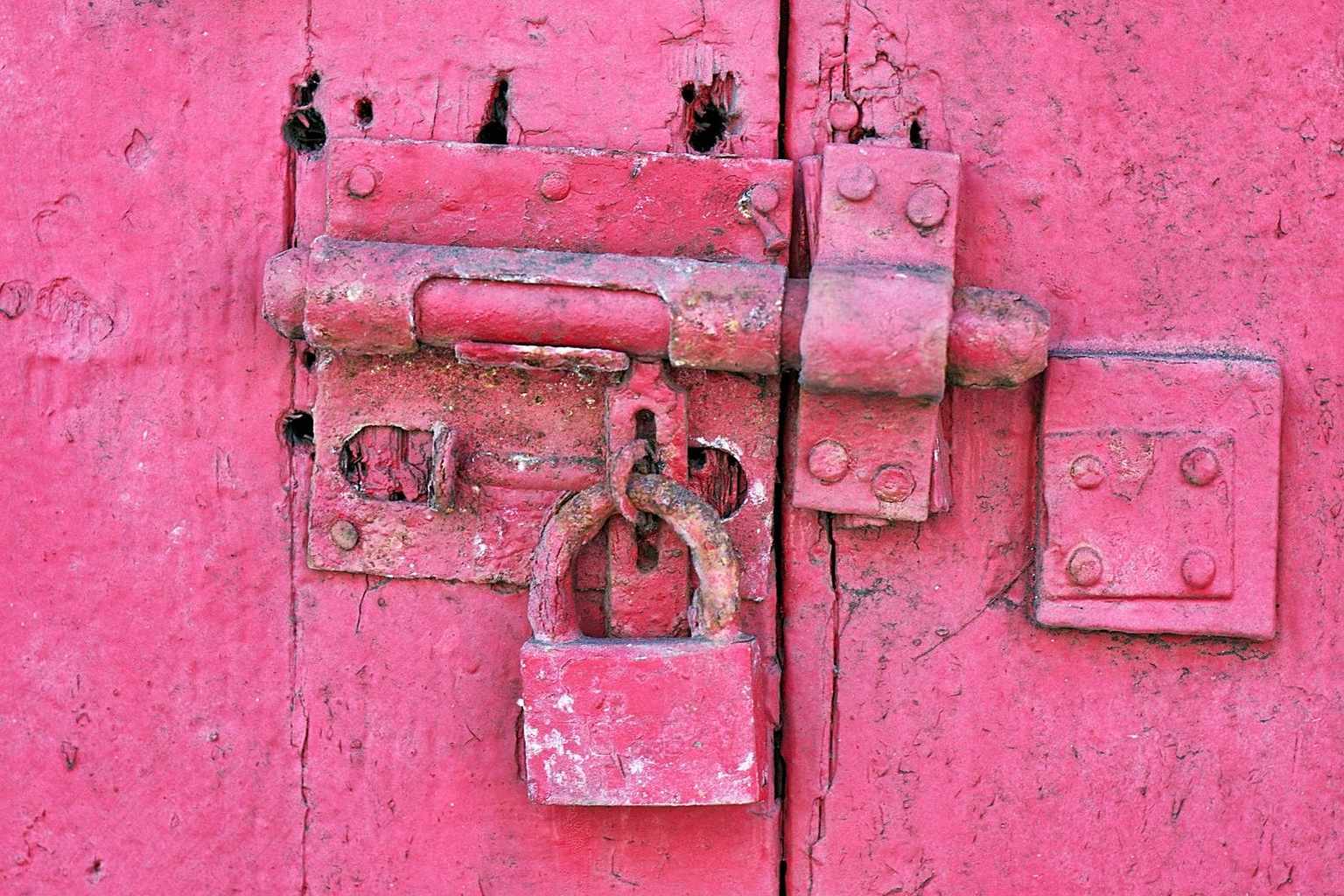 An old rusted padlock and bolt painted over in bright pink, a metaphor for an outdated PHP version hidden under a fresh WordPress theme and exposed to PHP2Shell