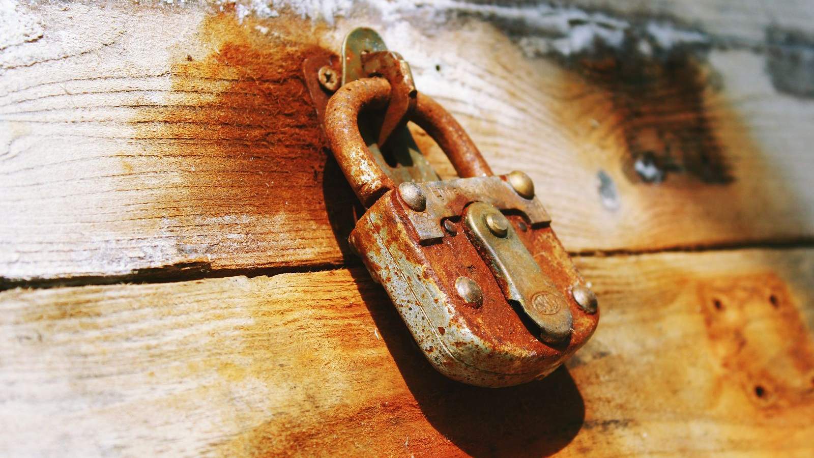 Rusty old padlock hanging on weathered wood, representing end-of-life PHP versions with no security fix for PHP2Shell