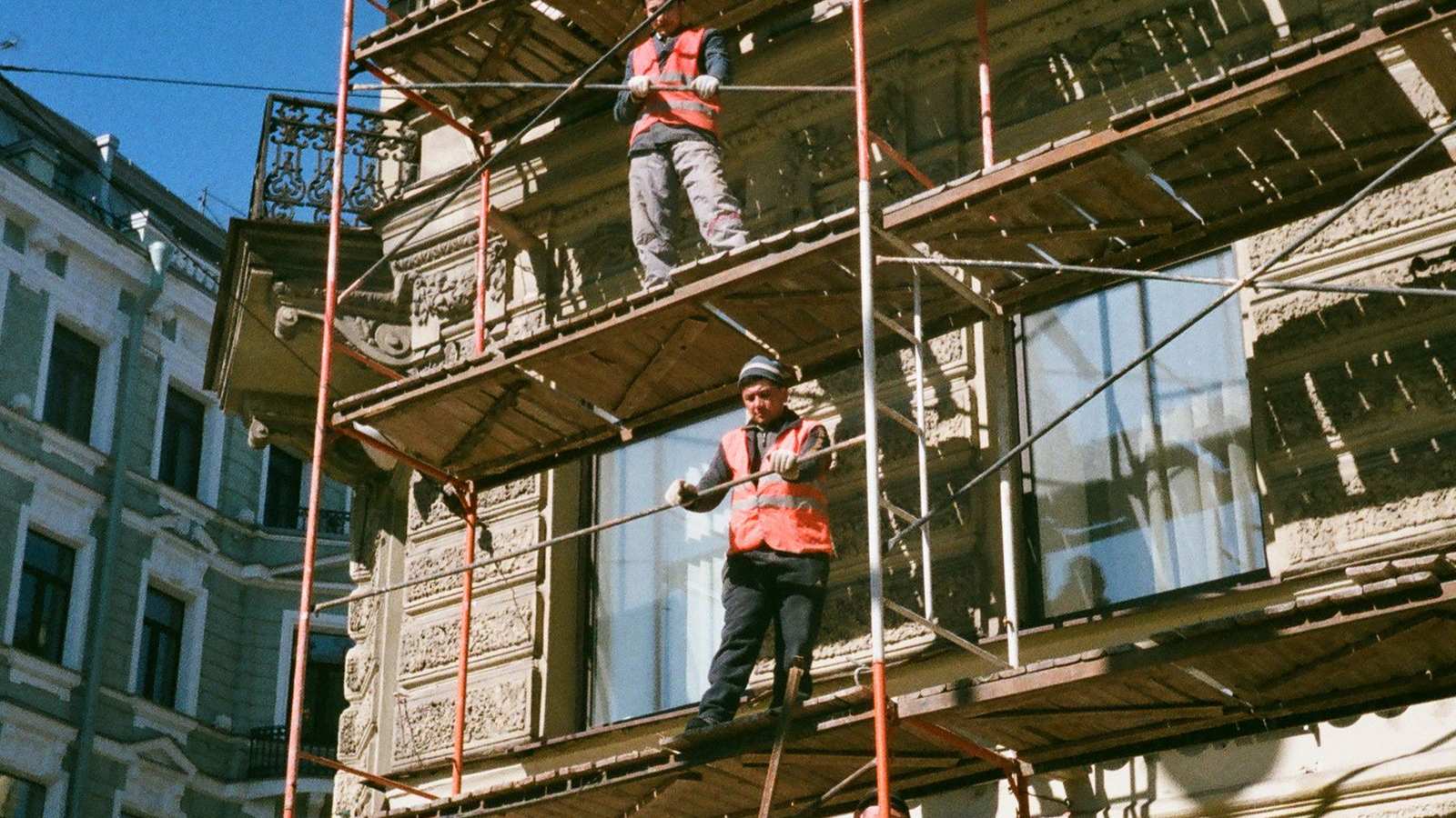 Workers on scaffolding renovating a building facade, a metaphor for a planned WordPress to Next.js and Strapi migration