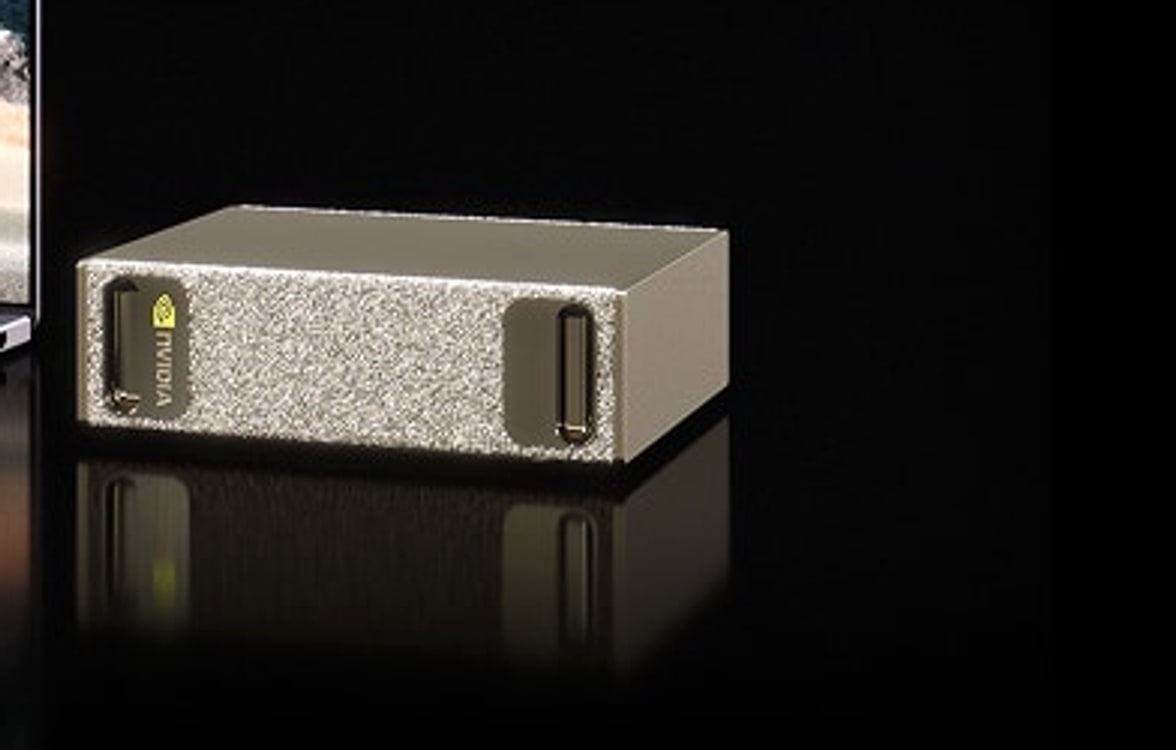 NVIDIA DGX Spark desktop AI supercomputer — a compact gold-mesh chassis beside a laptop